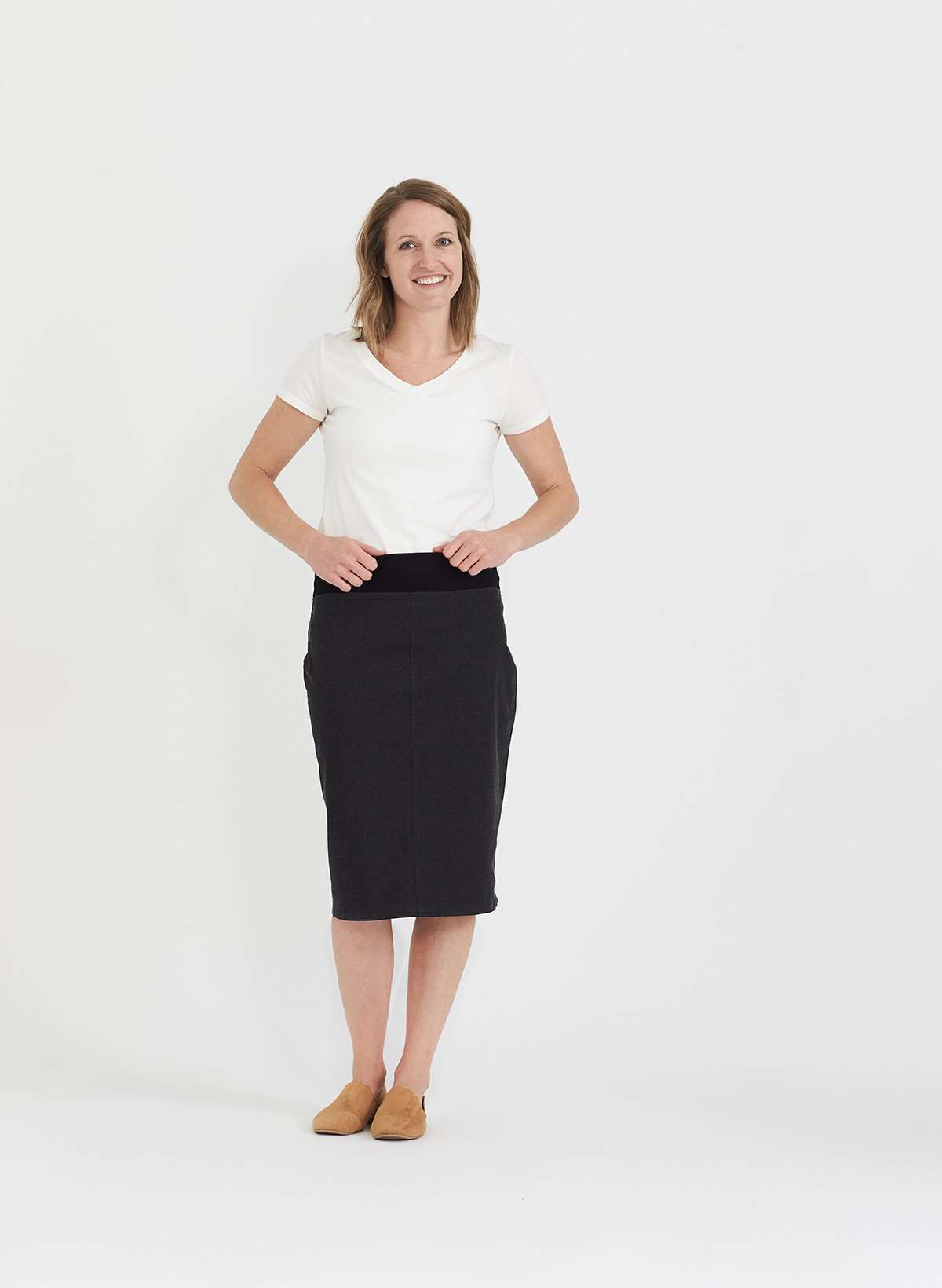 Woman wearing a colored, denim-like skirt with a elastic waistband. This is a modest skirt that falls below the knee. It comes in Burgundy, olive, khaki, black and navy. It is also paired with a white v-neck t-shirt.