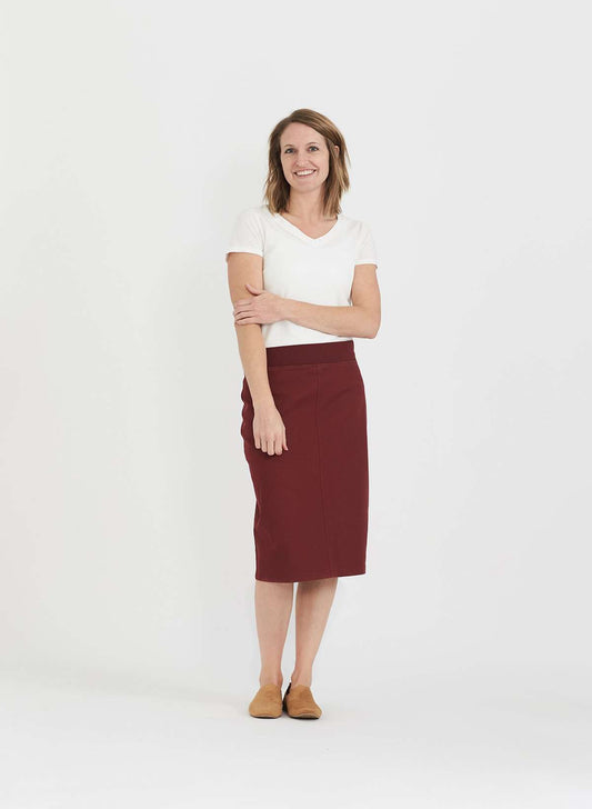 Woman wearing a colored, denim-like skirt with a elastic waistband. This is a modest skirt that falls below the knee. It comes in Burgundy, olive, khaki, black and navy. It is also paired with a white v-neck t-shirt.